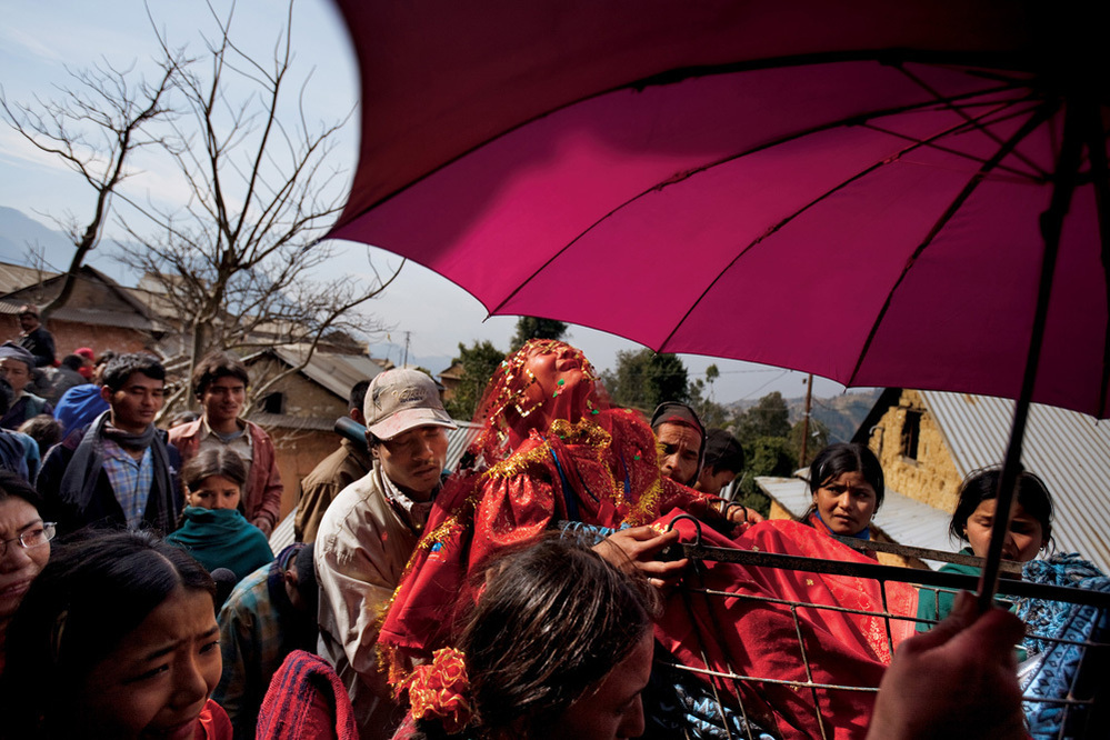 Although early marriage is the norm in her small Nepali village, 16-year-old Surita wails in protest as she leaves her family's home, shielded by a traditional wedding umbrella and carried in a cart to her new husband's village.
