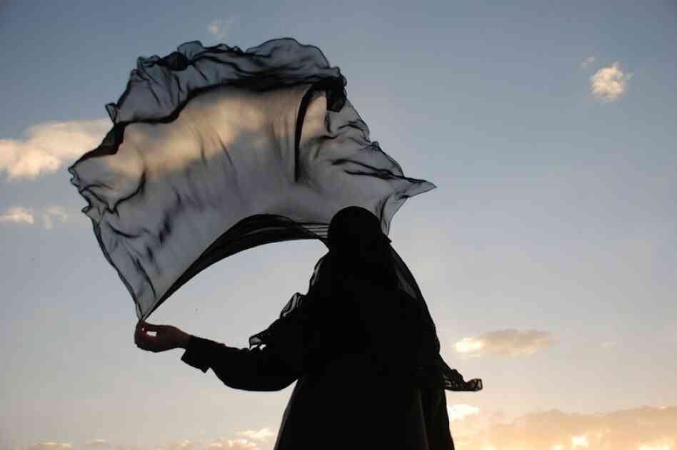 A woman in Yemen holds her veil. Photojournalist Amira Al-Sharif is undertaking a project that compares and contrasts the lives of young women in Yemen and the United States.