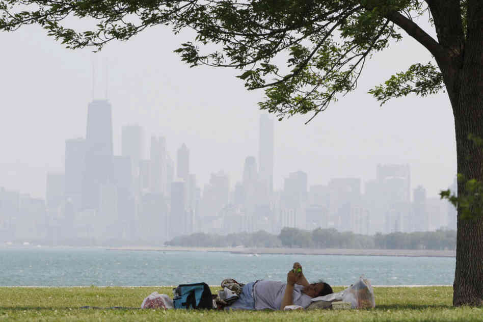 A woman rests in the shade at Montrose beach in Chicago. Cooling centers have opened in Chicago, Memphis, Tenn., and Newark, N.J., as a refuge for those without air conditioning. 
