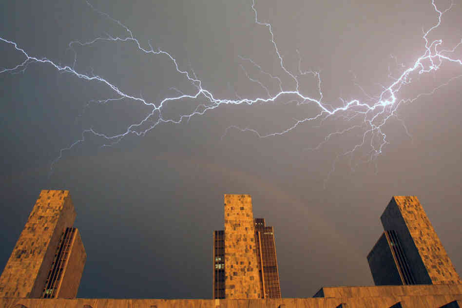 Heat lightning and a rainbow stretch across the sky over state agency buildings at the Empire State Plaza in Albany, N.Y. The mercury climbed into the 90s across half the country Wednesday. 