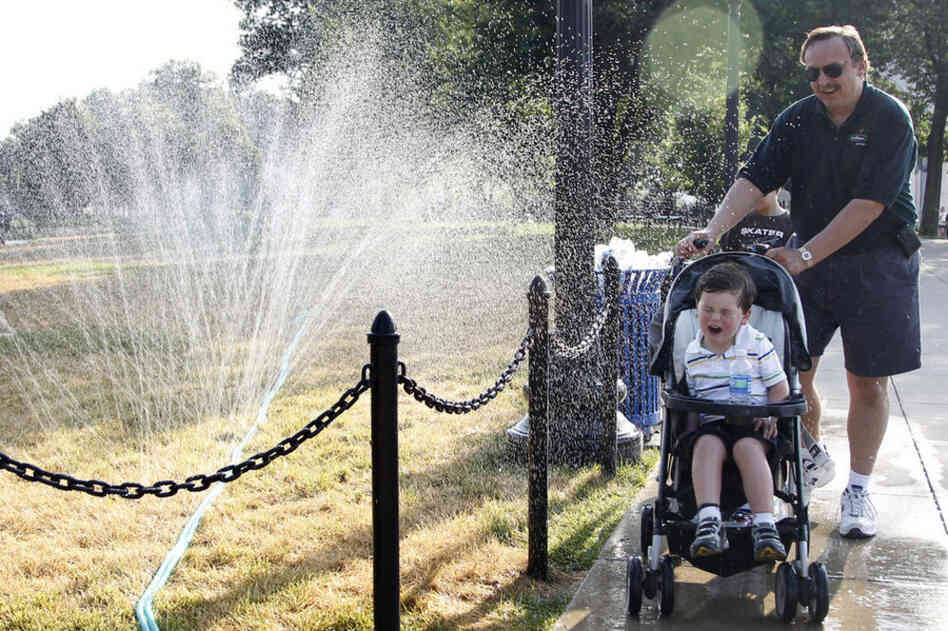 Ron Krajewski of San Diego, Calif., pushes his son through a water sprinkler to beat the simmering heat in Washington, D.C. 