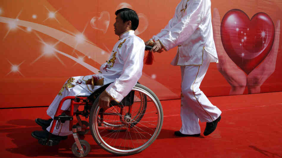 A man pushes a friend in a wheelchair following an event in Beijing to raise awareness of accessibility issues for the disabled. A man pushes a friend in a wheelchair following an event in Beijing to raise awareness of accessibility issues for the disabled.
