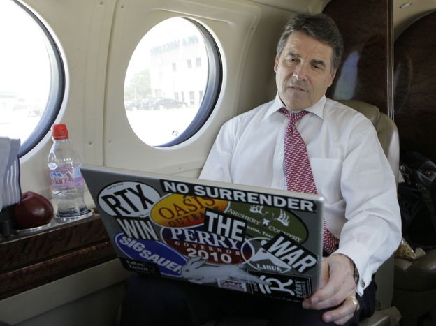 Texas Gov. Rick Perry  looks at his laptop aboard a jet in Addison, Texas, April 12, 2011.