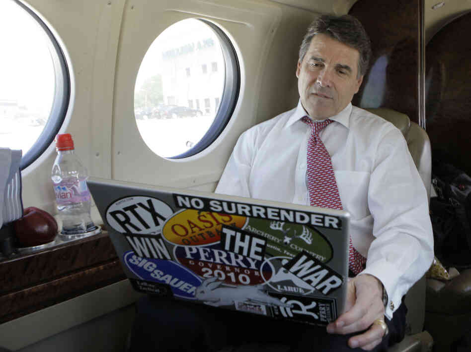 Texas Gov. Rick Perry  looks at his laptop aboard a jet in Addison, Texas, April 12, 2011.