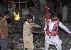 Rescue workers carry away a wounded man from the site of an explosion in Peshawar, Pakistan, early Sunday. Rescue workers carry away a wounded man from the site of an explosion in Peshawar, Pakistan, early Sunday.