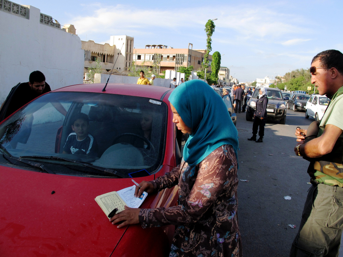 Volunteer Mabarka Mohammed al Mansouri, who manages the women-only gas station in Tripoli, checks the identification of one of the gas line patrons to make sure they haven't pumped gas in a week.