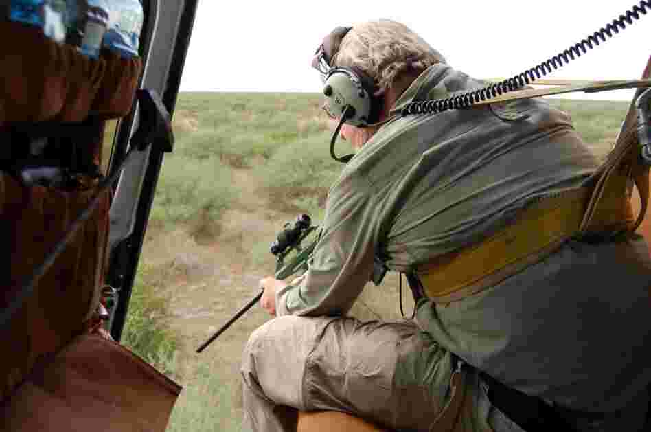Veterinarian Mike Kock aims his tranquilizer gun out of a helicopter at an elephant in the bush below. Kock works with the New York-based Wildlife Conservation Society studying where animals migrate in South Sudan to better protect them from poachers and development. 