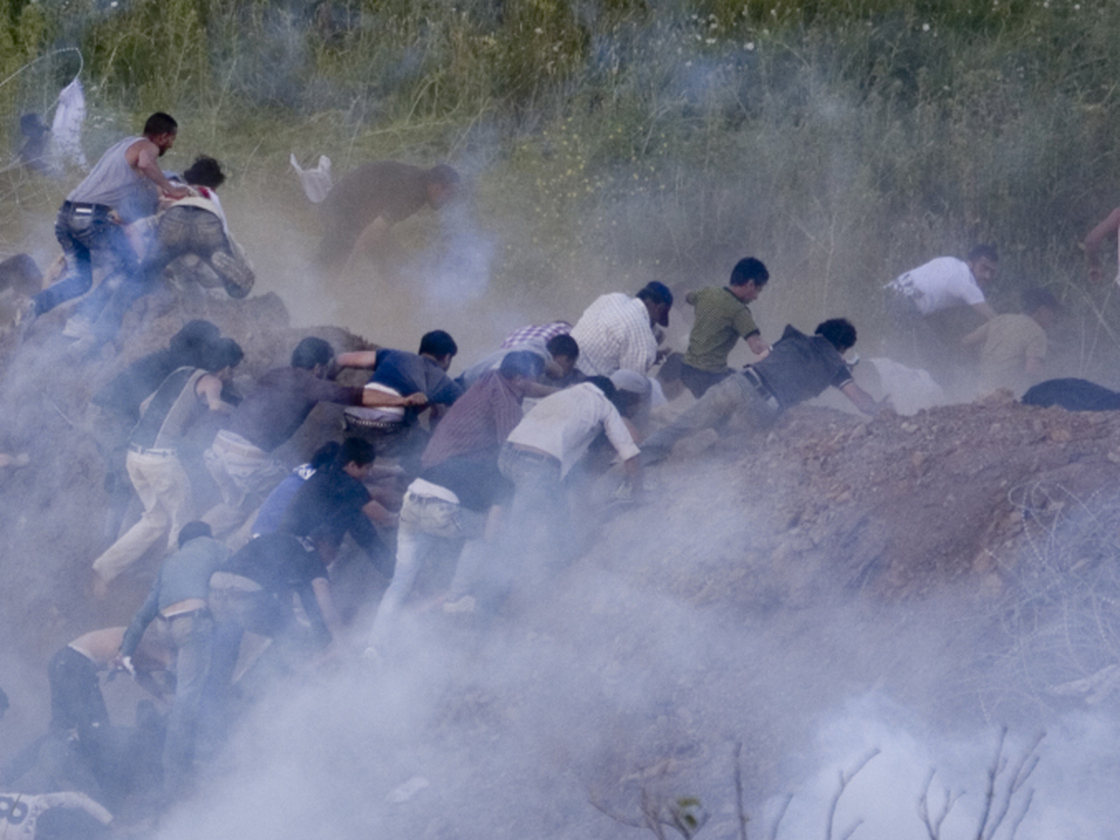 Pro-Palestinian protesters run from tear gas fired by Israeli troops along the border between Israel and Syria on June 5. Israeli troops battled hundreds of pro-Palestinian protesters who tried to burst across Syria's frontier with the Golan Heights, killing a reported 20 people and wounding scores more.