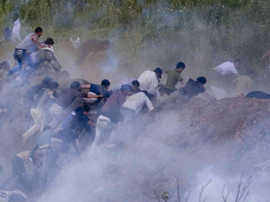 Pro-Palestinian protesters run from tear gas fired by Israeli troops along the border between Israel and Syria on June 5. Israeli troops battled hundreds of pro-Palestinian protesters who tried to burst across Syria's frontier with the Golan Heights, killing a reported 20 people and wounding scores more.