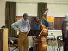 Ron Carter (left, as himself) looks on as Albert Lambreaux (Clarke Peters) attempts to show him a thing or two on bass, in Treme.