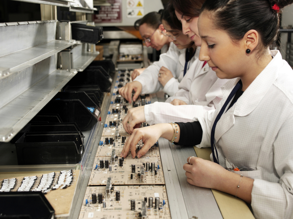 Workers with circuit boards on a production line.