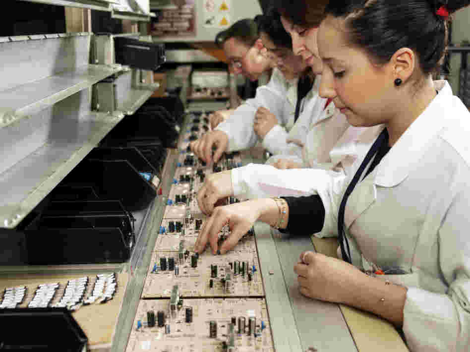 Workers with circuit boards on a production line.