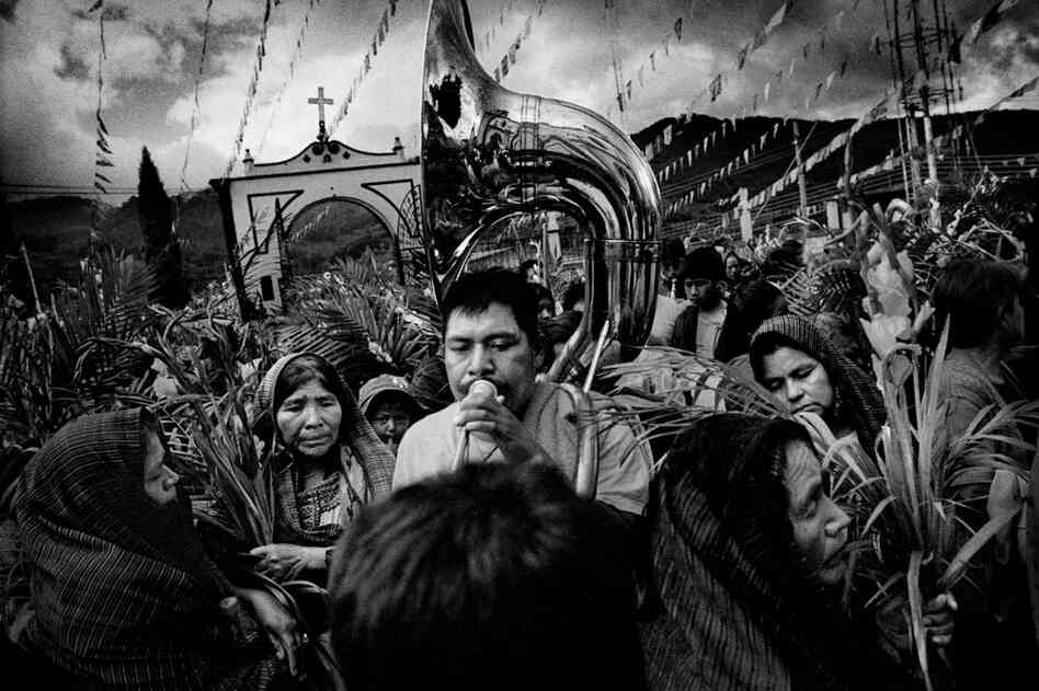A returned migrant leads a Saint's Day celebration to the church plaza.