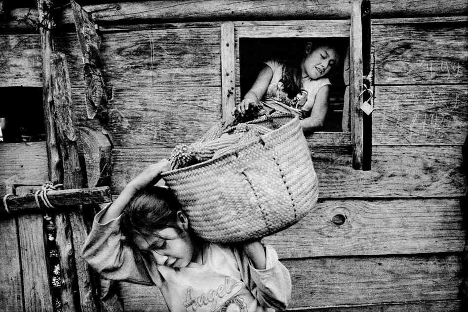 Sisters empty corn from their family's crib.