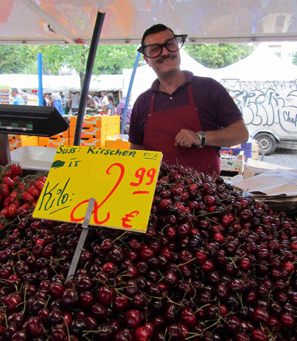 A vendor sells cherries at the Market. A vendor sells cherries at the Market.