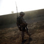 A Marine walks along a mud wall while conducting a search and clearing operation in Afghanistan's Helmand province, as the dust from a wheat thrashing machine falls like snow. A Marine walks along a mud wall while conducting a search and clearing operation in Afghanistan's Helmand province, as the dust from a wheat thrashing machine falls like snow.