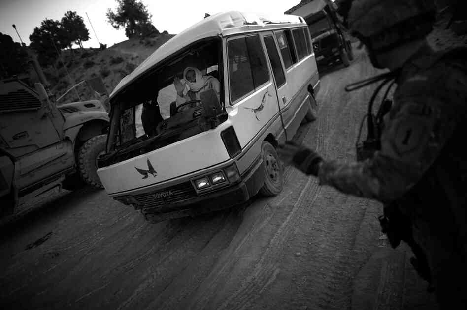 A soldier with Butcher Troop waves to a driver who rolled his bus earlier in the day on the dangerous switchbacks section of the Khost-Gardez highway in Paktia province.