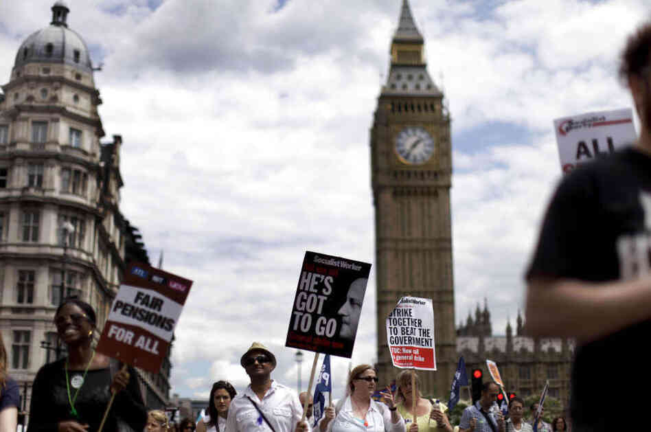 People march past the Houses of Parliament with placards as they take part in a protest to mark the nationwide day of strikes in London.