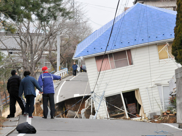 Residents check an earthquake-damaged house in Sukagawa city on March 11, in the Fukushima prefecture in Japan. A researcher says that after large-scale natural disasters, it's frequently friends and neighbors who are key to survival.