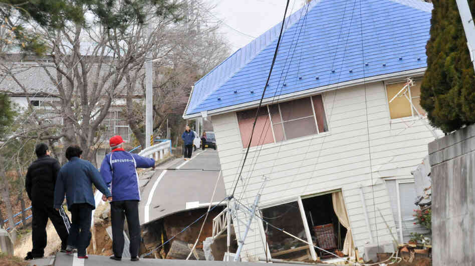 Residents check an earthquake-damaged house in Sukagawa city on March 11, in the Fukushima prefecture in Japan. A researcher says that after large-scale natural disasters, it's frequently friends and neighbors who are key to survival.