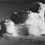 A member of the Terra Nova Expedition (or British Antarctic Exploration team) travels by dogsled in front of a weathered iceberg, circa 1910 or 1911. A member of the Terra Nova Expedition (or British Antarctic Exploration team) travels by dogsled in front of a weathered iceberg, circa 1910 or 1911.