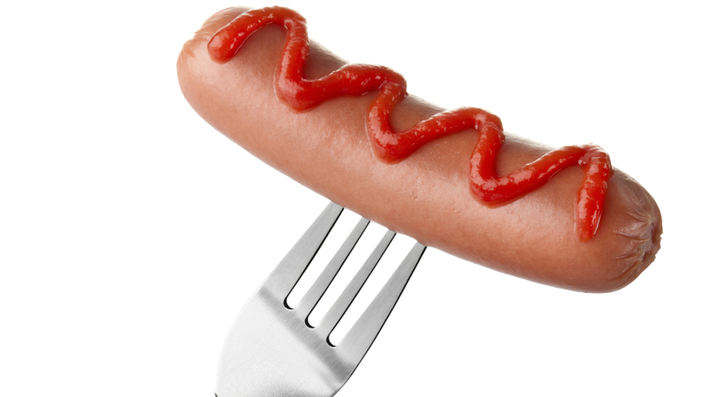 Hot dog on fork with ketchup topping.