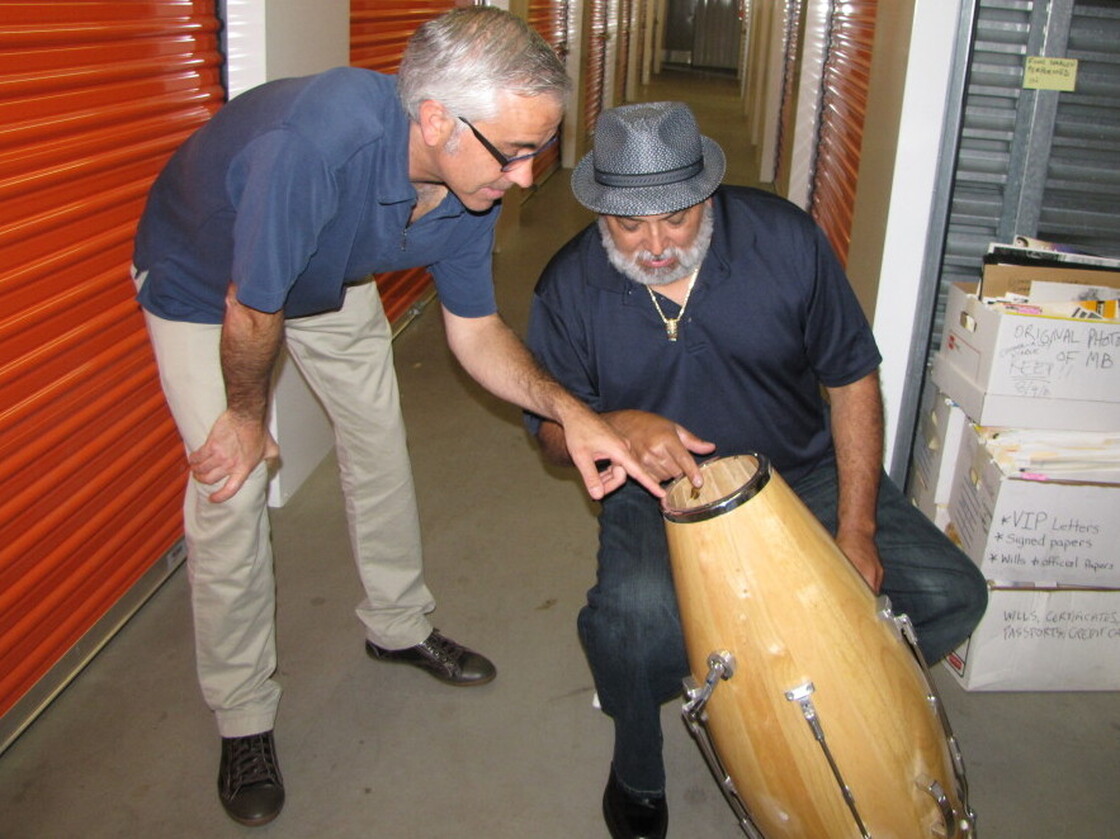 Attorney Kevin Costanza and drummer Poncho Sanchez examine one of Brando's patented conga-tuning devices.