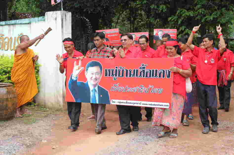 A Buddhist monk sprinkles holy water on Red Shirt leaders  as they parade through Baan Suksomboon in northeastern Thailand's Udon  Thani province. Baan Suksomboon is  Thailand's 255th  Red Village to declare its support for  opposition candidate Yingluck Shinawatra. Thaksin Shinawatra, pictured on the  campaign poster, jokingly calls his sister his "clone."