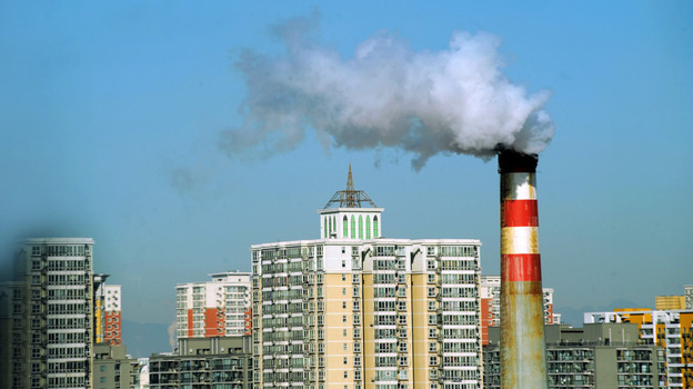 Pollutants billow out of a chimney amid a group of residential housings in Beijing.