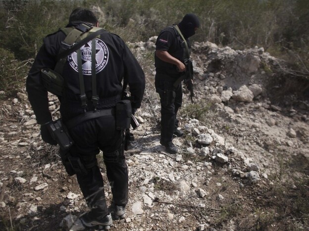 Police officers stand next to a hole they say was used as a mass grave near San Fernando in the Mexican state of Tamaulipas in late April. Almost 200 bodies were found that month in Tamaulipas. Prosecutors believe the killings were carried out by members of the Zetas drug cartel.