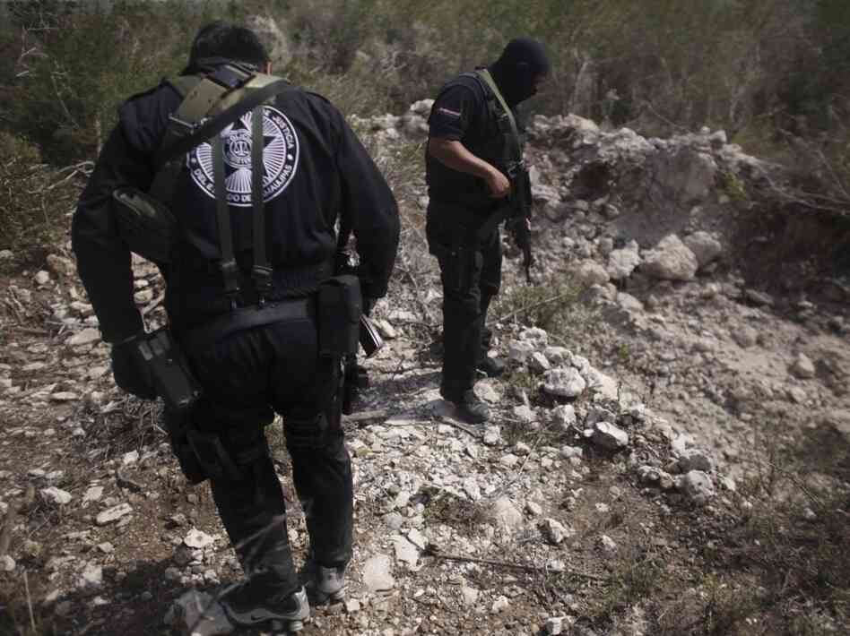 Police officers stand next to a hole they say was used as a mass grave near San Fernando in the Mexican state of Tamaulipas in late April. Almost 200 bodies were found that month in Tamaulipas. Prosecutors believe the killings were carried out by members of the Zetas drug cartel.