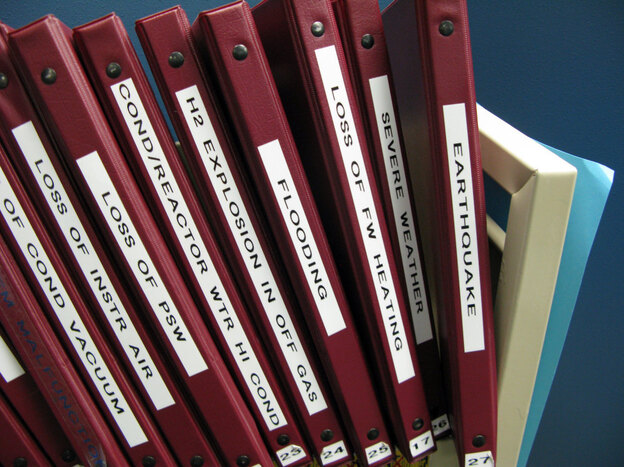 A shelf in the control room simulator holds binders of protocols for how to handle emergency situations.