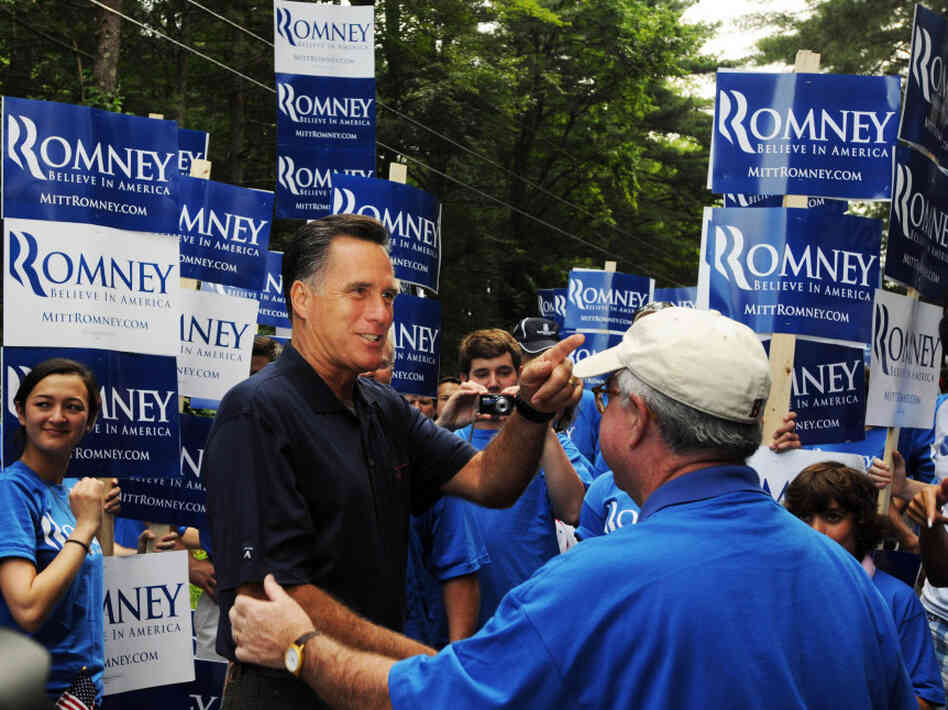 Former Massachusetts Gov. Mitt Romney shakes hands while marching in the Fourth of July parade in Amherst, N.H.