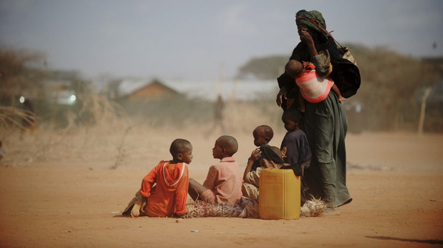 Sarura Ali (right) covered her eyes from wind-blown dust as she stood with her six children outside a food distribution point in the Dadaab refugee camp in northeastern Kenya on Tuesday (July 5, 2011). Sarura, her husband and their children trekked for eight days from their home in Sakow, Somalia. War and drought are forcing many Somalis to take desperate measures.