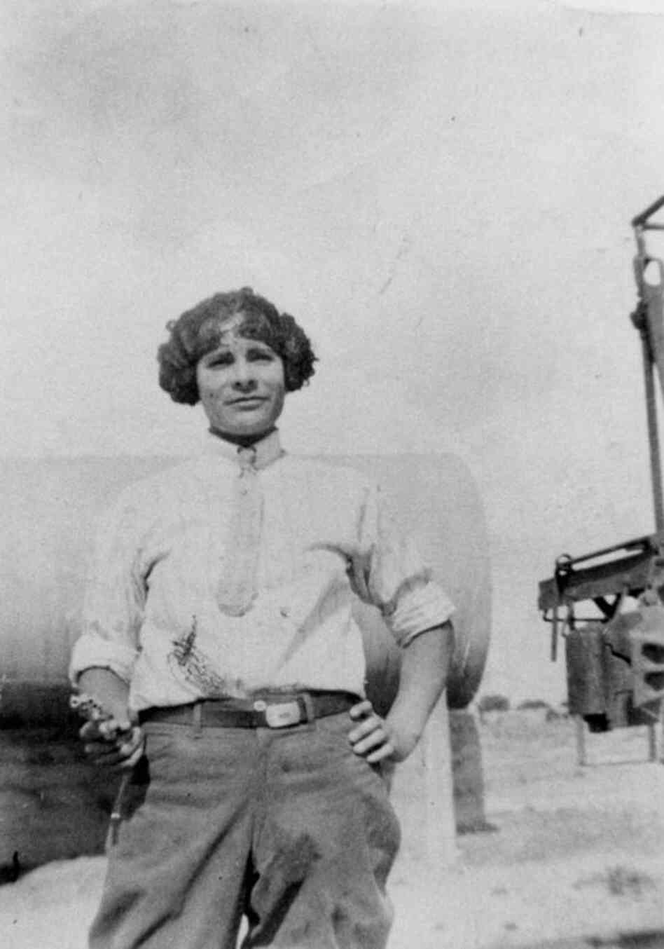 A woman wears pants and wields a gun in the 1920s.