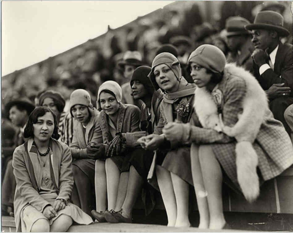 Six Howard University students watch a football game in the 1920s.