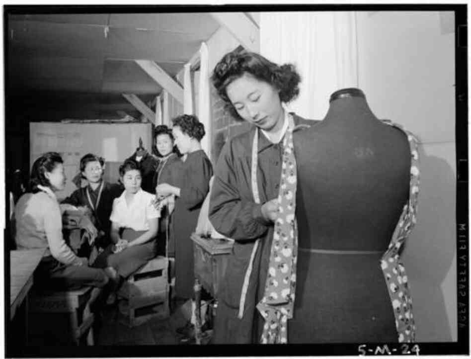 This photograph was taken by Ansel Adams at the Manzanar War Relocation Center in California, where Japanese-Americans were interned during World War II. A woman identified as Riye Yoshizawa is in a dressmaking class. According to "Of Another Fashion," she later helped open the Modern School of Fashion in Southern California.