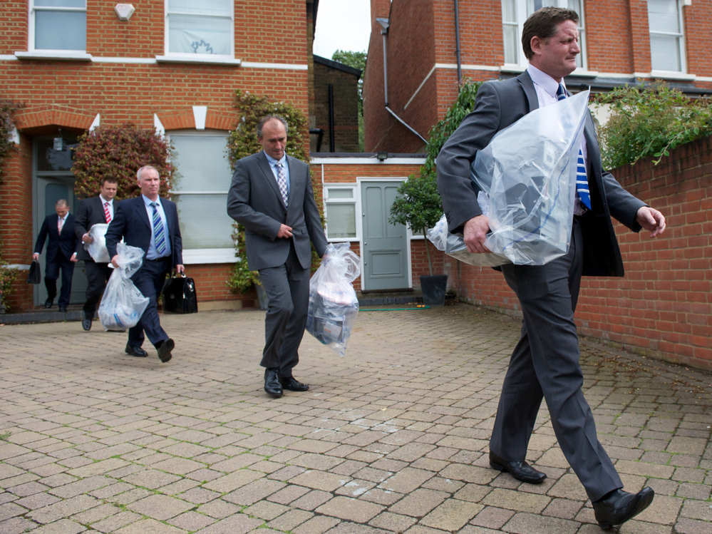 Investigators carry bags of evidence from the home of Andy Coulson, a former News of the World editor and Cameron aide, in London on Friday. Police arrested Coulson in the phone hacking scandal.