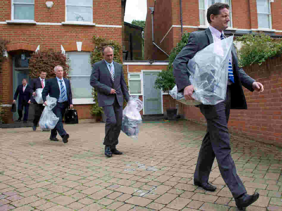 Investigators carry bags of evidence from the home of Andy Coulson, a former News of the World editor and Cameron aide, in London on Friday. Police arrested Coulson in the phone hacking scandal.
