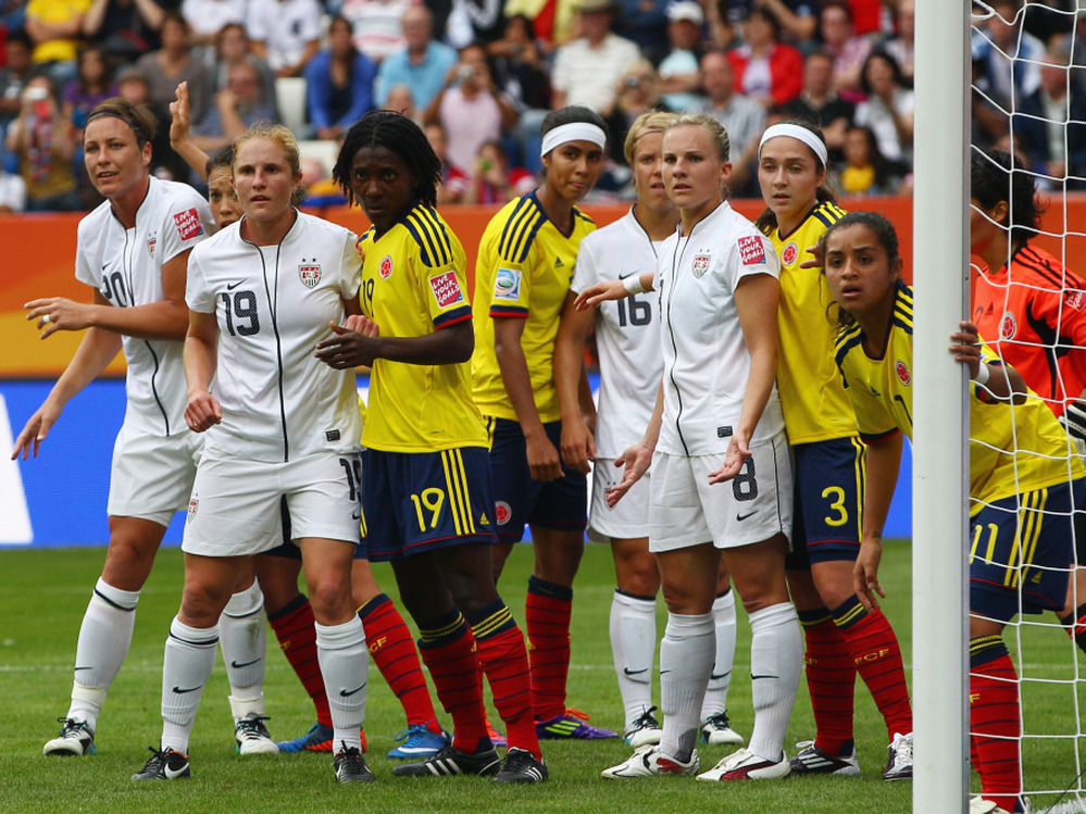 U.S. players, in white, line up for a corner kick against Colombia in a group stage game of the 2011 Women's World Cup. The white jerseys have been criticized as resembling a nurse's uniform.