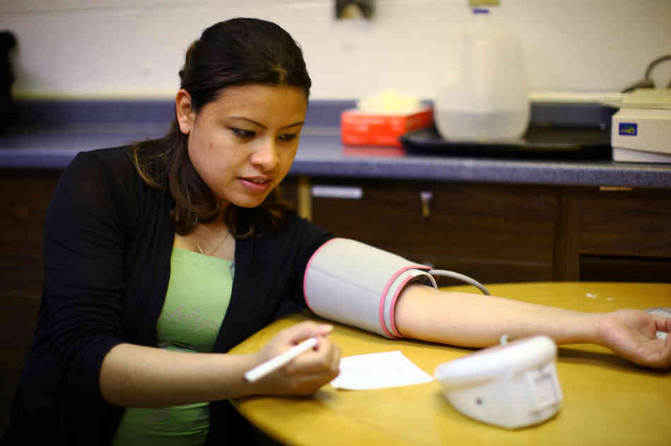 Andrea Lopez  takes her own blood pressure at the group meeting. The women meet every two weeks for two hours throughout their pregnancy to learn how to monitor their own health and talk about different pregnancy-related issues.