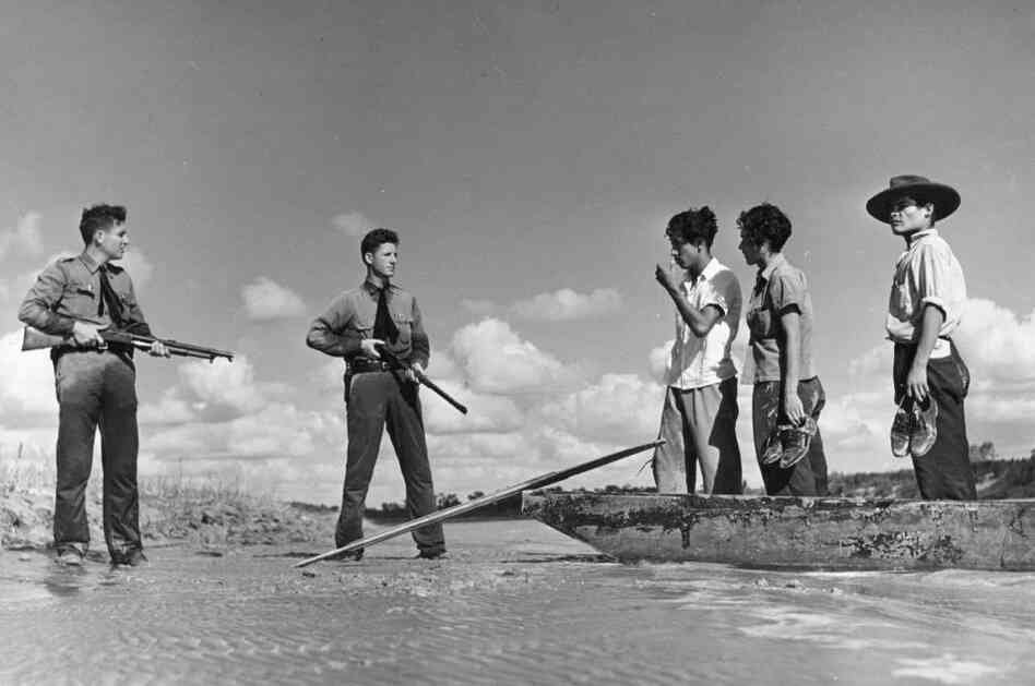 Two armed American border guards confront a group of immigrants attempting to cross illegally from Mexico into the United States in 1948. In A Line in the Sand, Rachel St. John traces the history of the U.S.-Mexico border.