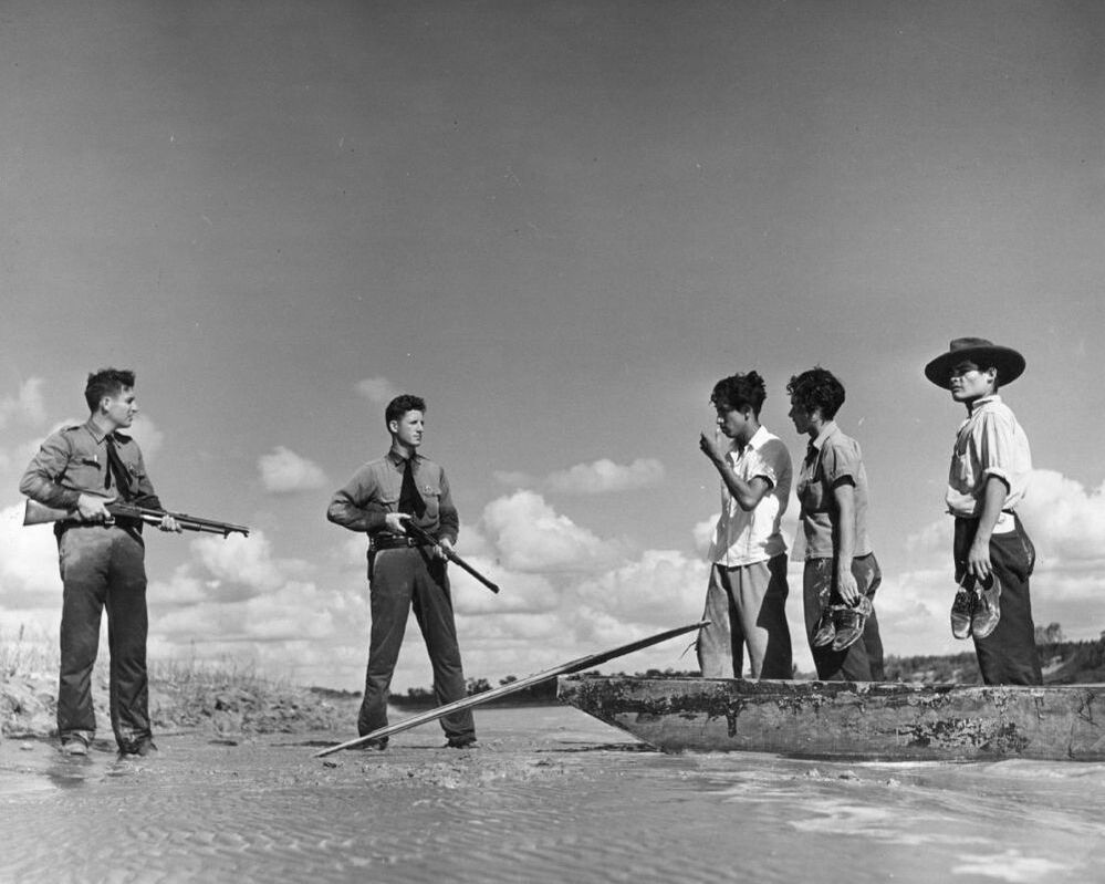 Two armed American border guards confront a group of immigrants attempting to cross illegally from Mexico into the United States in 1948. In A Line in the Sand, Rachel St. John traces the history of the U.S.-Mexico border.