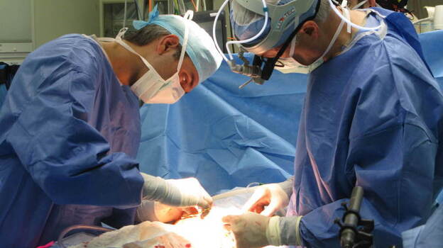 Surgical fellow Pablo Laje (left) and Dr. Scott Adzick finish prenatal surgery on Sarah White. Her fetus has spina bifida — a hole in the lower back that exposes the spinal cord.