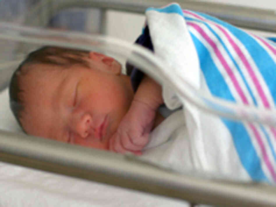 A photo of a newborn in the hospital with the standard pink-and-blue striped receiving blanket. A photo of a newborn in the hospital with the standard pink-and-blue striped receiving blanket.