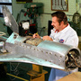A worker tests components on a model of the space shuttle before wind tunnel testing. A worker tests components on a model of the space shuttle before wind tunnel testing.