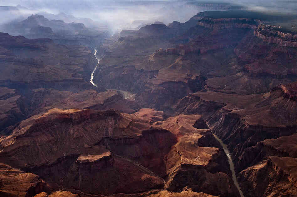 Looking east through a dawn wildfire haze, the Grand Canyon Village sits on the South Rim (right) of Grand Canyon National Park. First protected as a game preserve by President Theodore Roosevelt, the park was finally created in 1919.