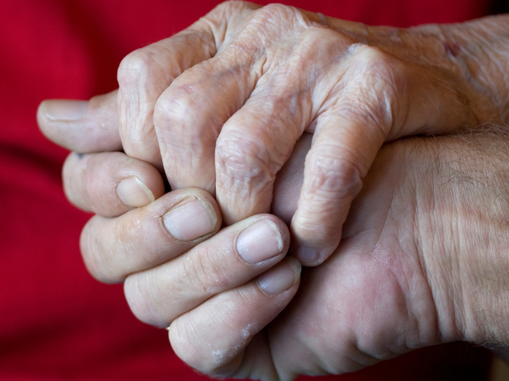 A son holding his elderly mother's hand.