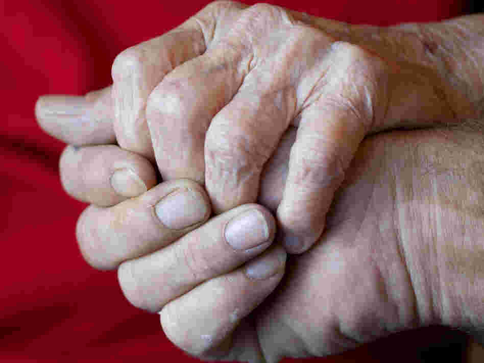 A son holding his elderly mother's hand.
