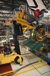 An engine is removed from space shuttle Endeavour after its final mission. Lookalike engines will replace the real ones when the shuttles go on display.